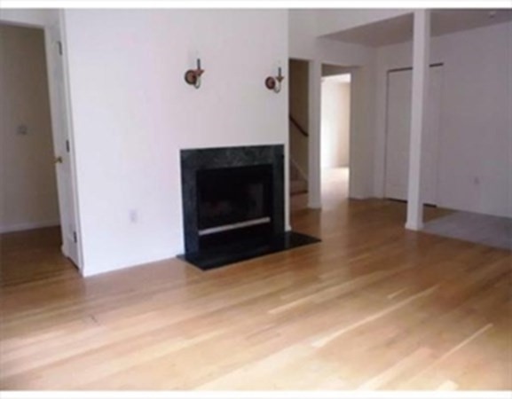 12 N Commons, Unit L Lincoln, MA 01773 - Photo 6 of 25 a view of an empty room with wooden floor and a fireplace
