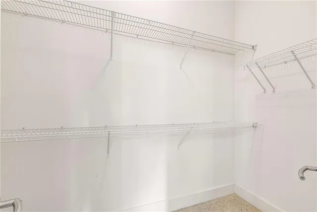 a view of an empty room with wooden floor and a ceiling fan