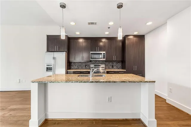 a large kitchen with stainless steel appliances kitchen island a large counter top and wooden floor