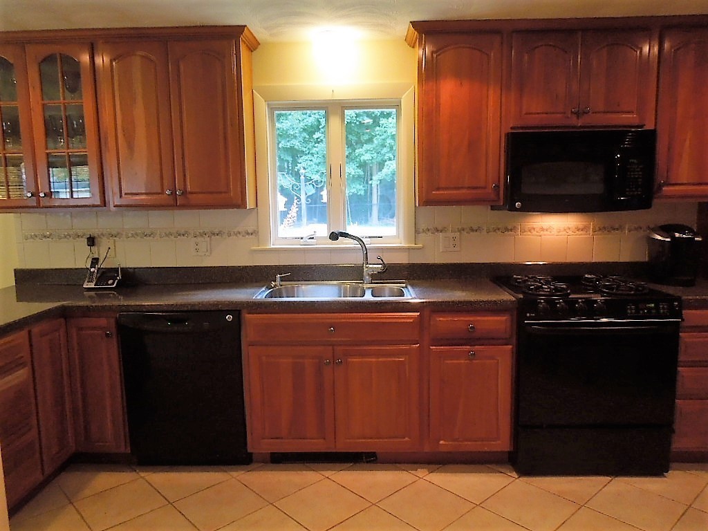 8 Howard Road Chelmsford, MA 01824 - Photo 10 of 30 a kitchen with granite countertop a stove a microwave a sink and cabinets