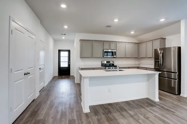 a kitchen with stainless steel appliances granite countertop a refrigerator a sink dishwasher a stove and white countertops with wooden floor
