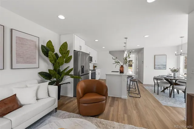 a living room with furniture a potted plant and open kitchen view