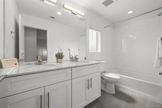 a bathroom with a double vanity sink a toilet and a bathtub
