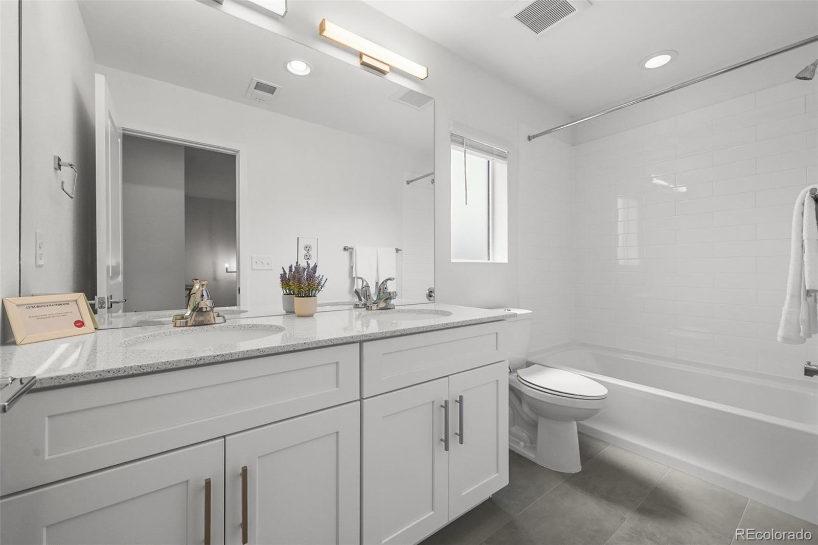 1304 Akron Street Aurora, CO 80010 - Photo 18 of 28 a bathroom with a double vanity sink a toilet and a bathtub