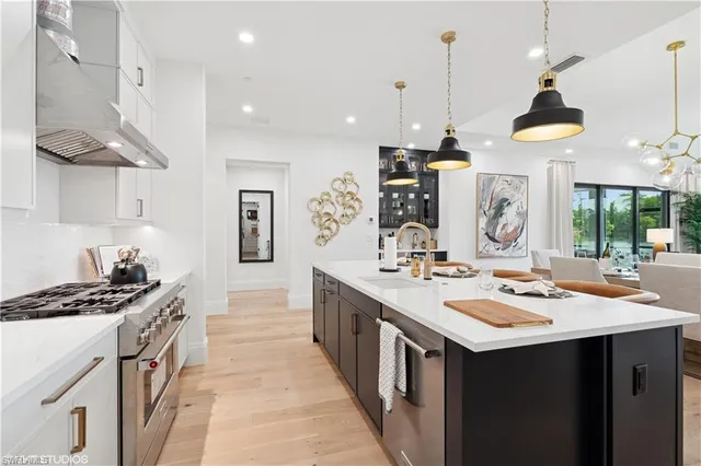 a kitchen with kitchen island stainless steel appliances a sink a stove and a wooden floor