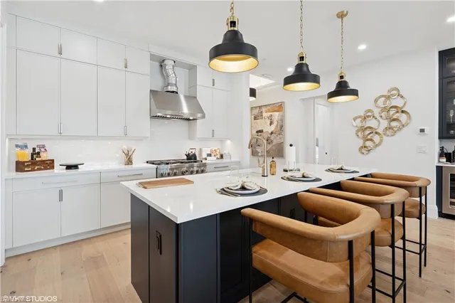 a kitchen with a sink a stove and chairs with wooden floor