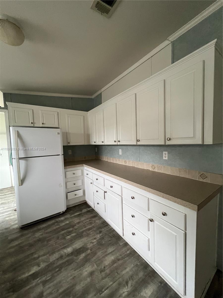 a kitchen with granite countertop white cabinets and refrigerator