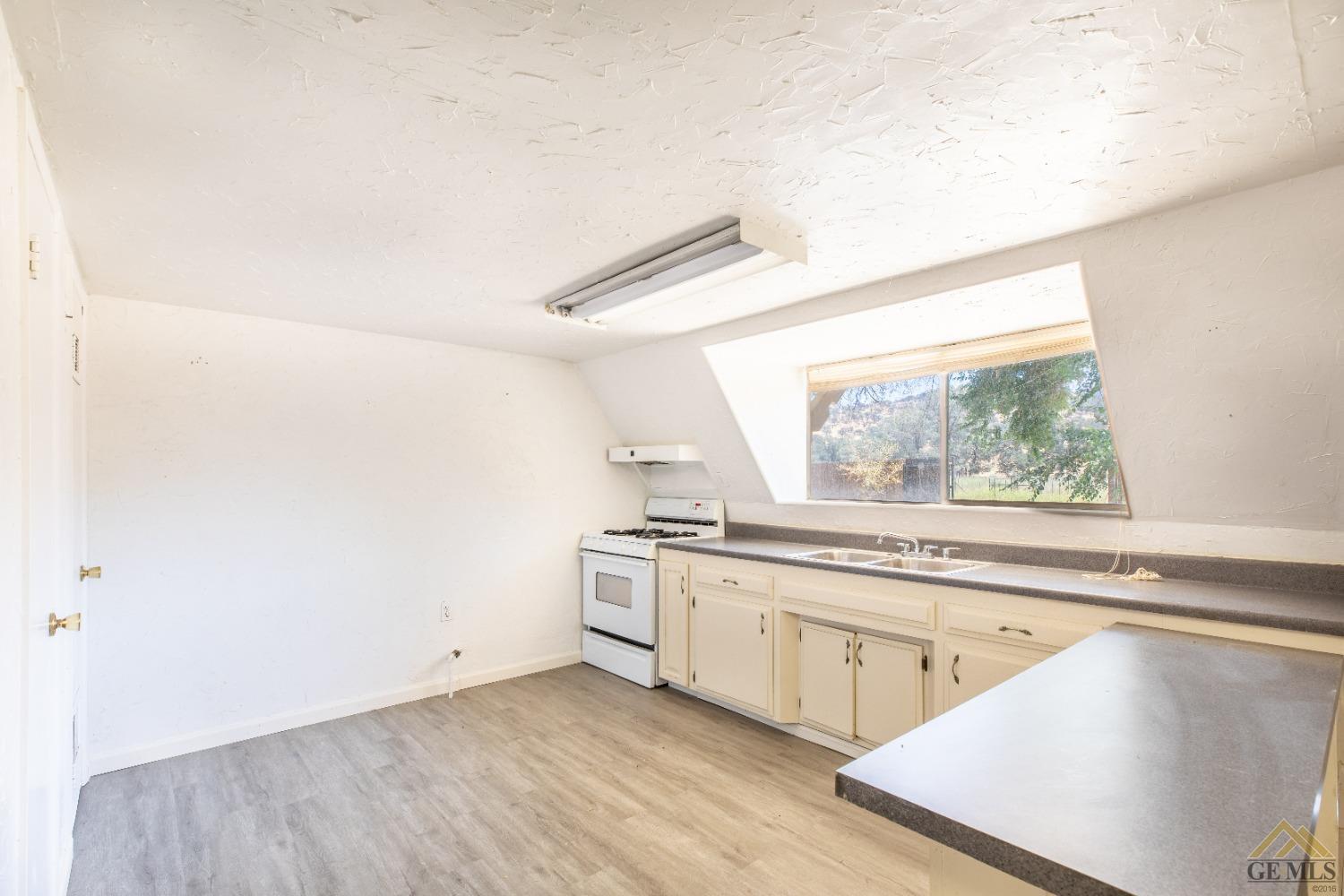Undisclosed Address Caliente, CA 93518 - Photo 56 of 59 a kitchen with a stove a sink and white cabinets with wooden floor next to windows