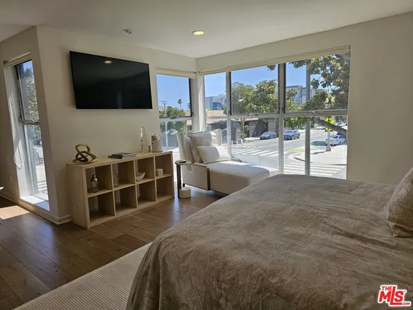 a living room with furniture a flat screen tv and floor to ceiling window