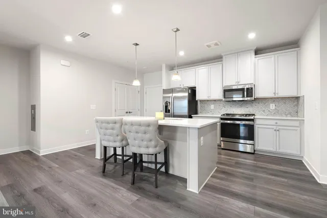 a kitchen with stainless steel appliances white cabinets and a stove top oven
