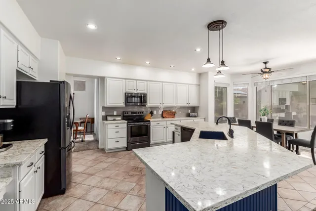 a kitchen with stainless steel appliances kitchen island granite countertop a stove refrigerator and cabinets