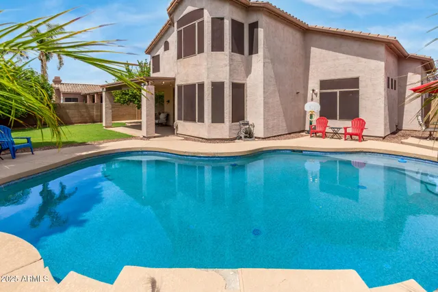a view of a house with pool and chairs