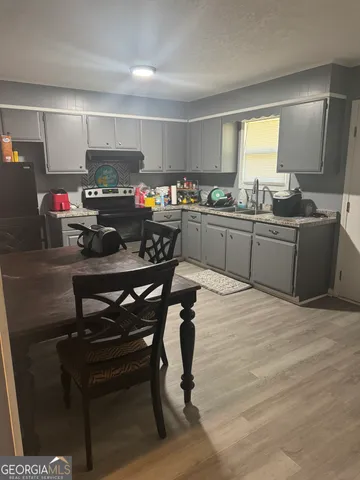 a kitchen with stainless steel appliances kitchen island granite countertop a table chairs sink and cabinets