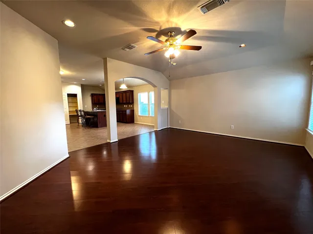 an empty room with wooden floor and chandelier fan