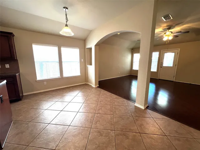 a view of an empty room with window and wooden floor
