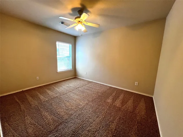 an empty room with a chandelier fan and windows
