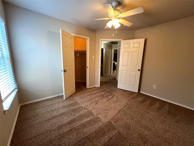 an empty room with closet and a ceiling fan