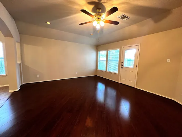 a view of an empty room with wooden floor and a window