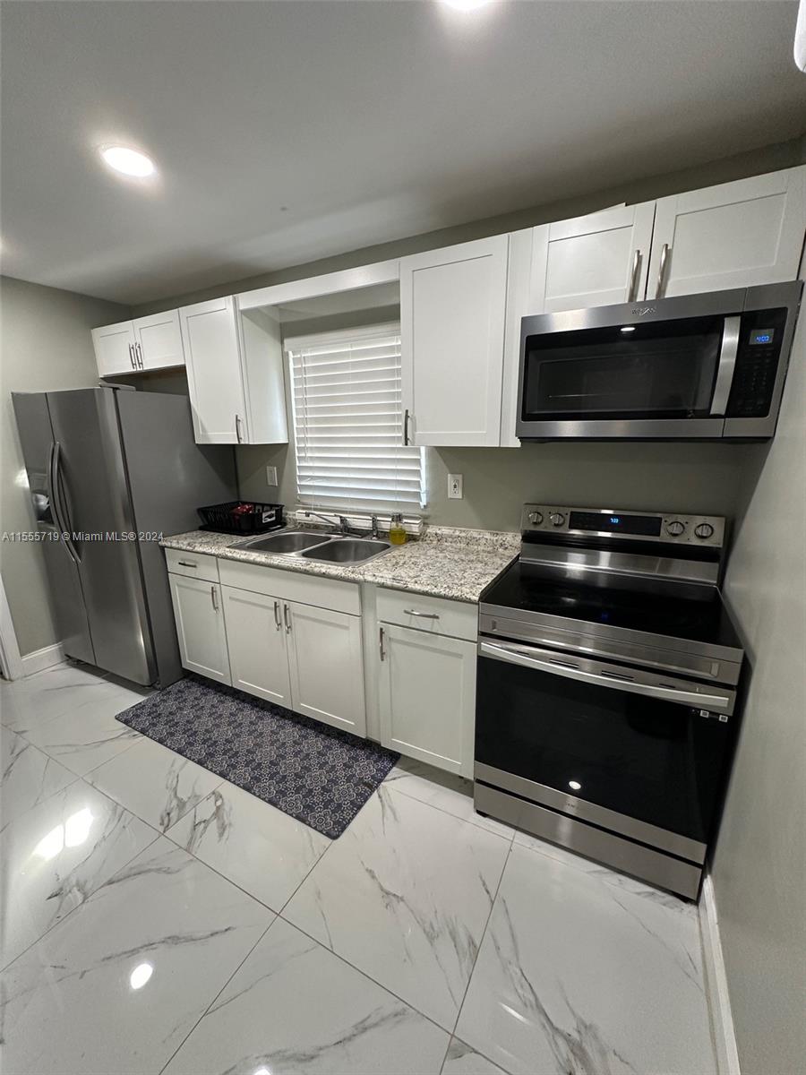 a kitchen with stainless steel appliances a sink a stove a microwave and cabinets