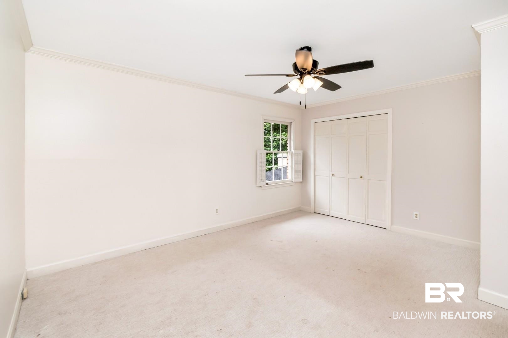4776 Falls Church Road Mobile, AL 36608 - Photo 23 of 45 Neutral-toned room featuring a ceiling fan with integrated lighting, a window with exterior tree scenery, and bi-fold closet doors