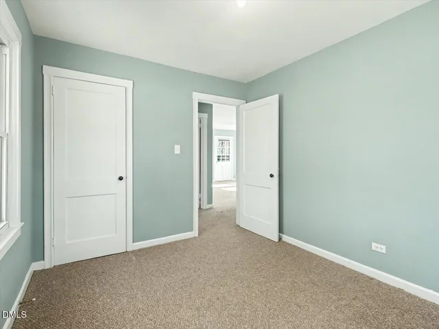 a view of an empty room with closet and a window