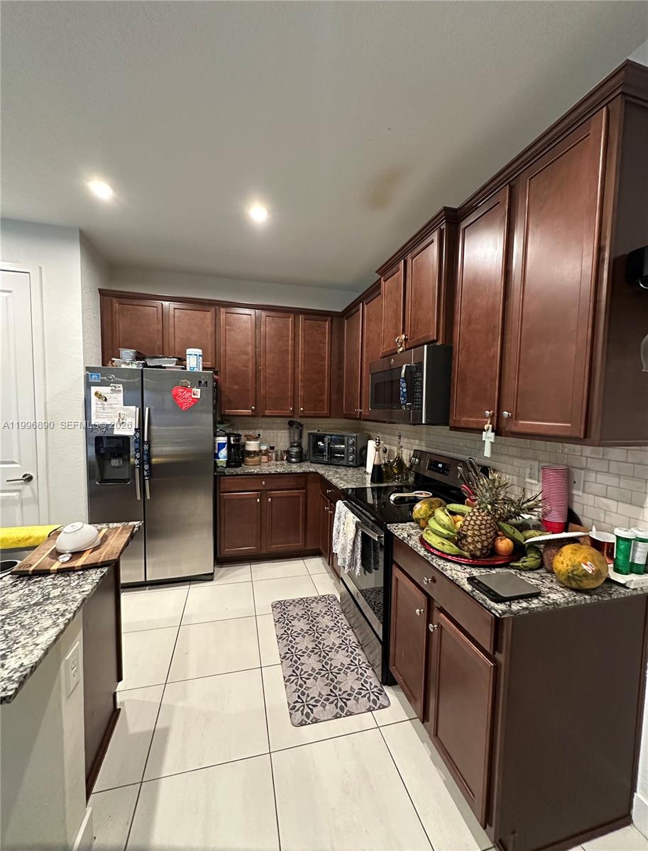 23552 Southwest 107th Place Homestead, FL 33032 - Photo 15 of 30 a kitchen with stainless steel appliances granite countertop a stove a sink dishwasher and a refrigerator