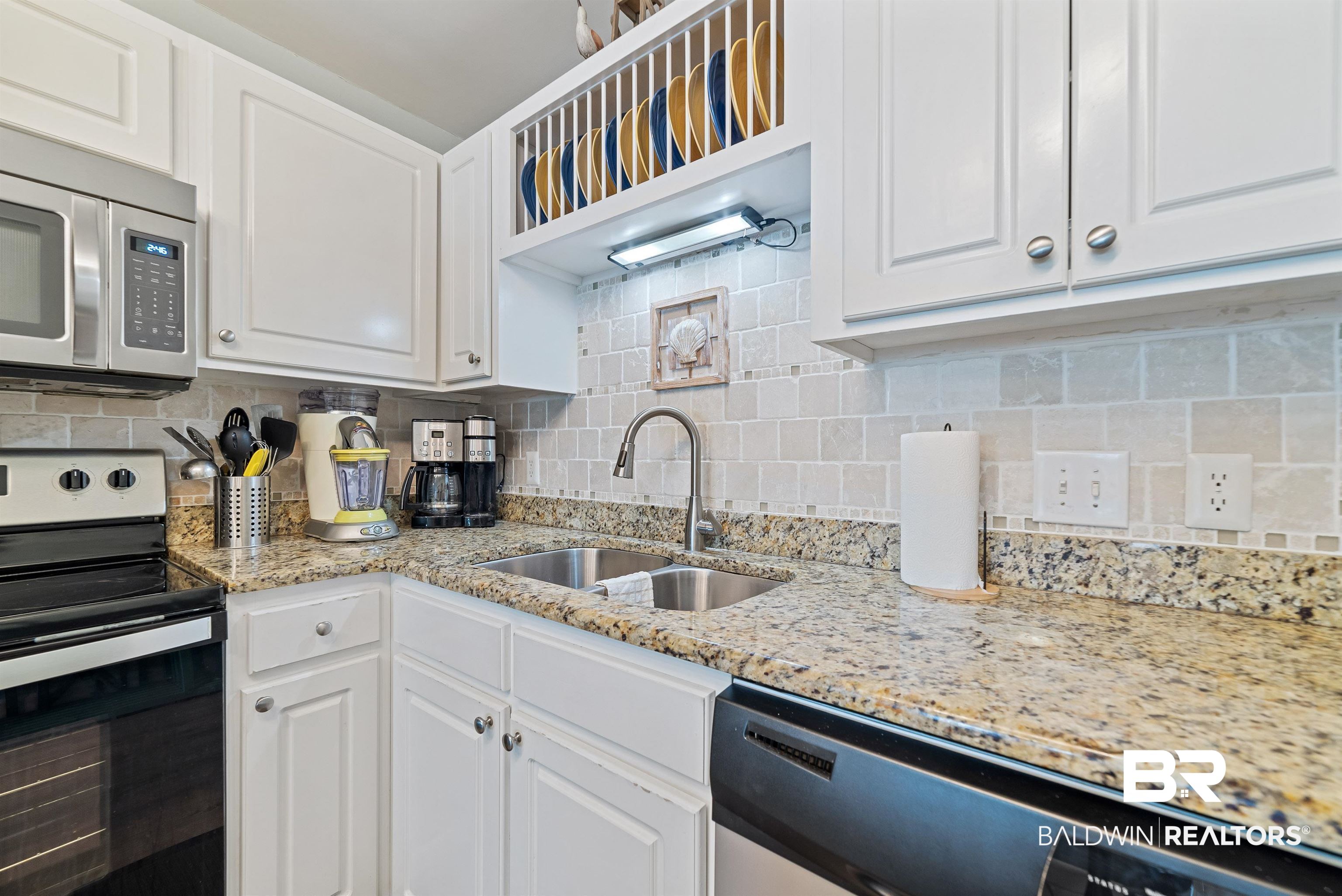 400 Plantation Road, Unit 2123 Gulf Shores, AL 36542 - Photo 5 of 44 Kitchen with white cabinetry, backsplash, light stone countertops, appliances with stainless steel finishes, and sink