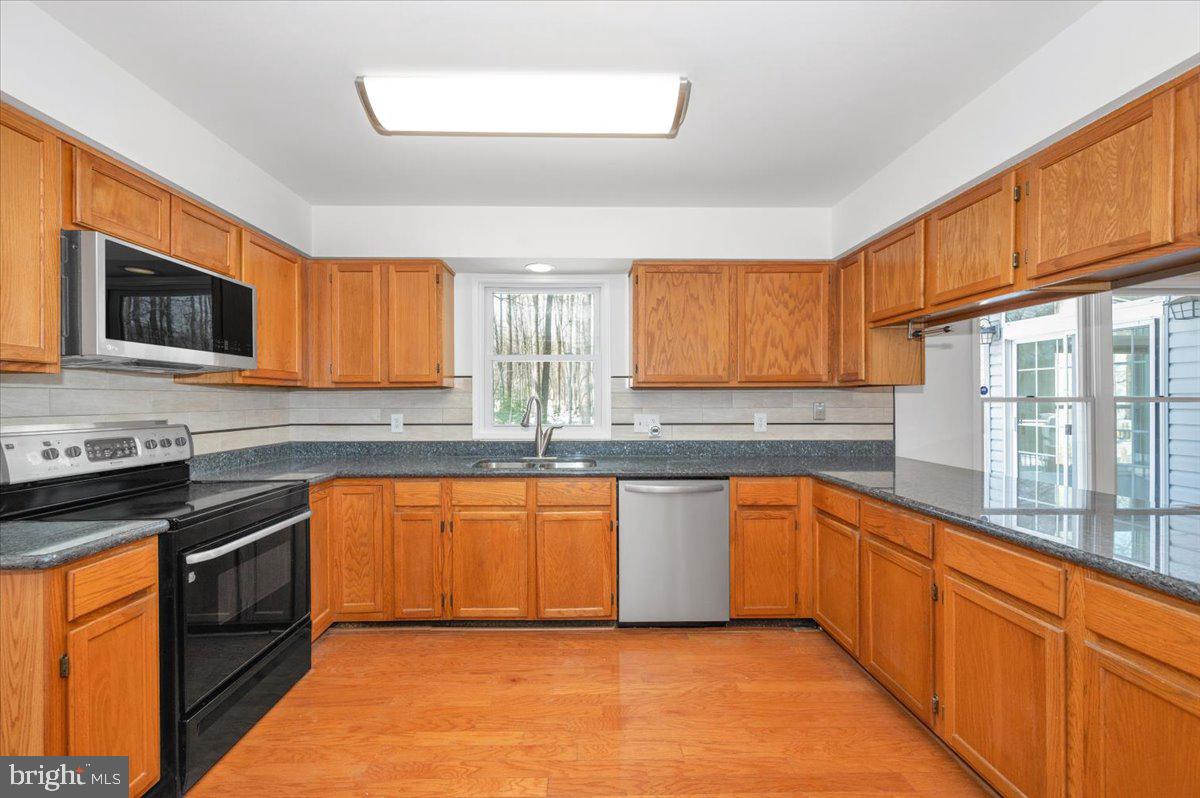1404 Partridge Lane Bowie, MD 20721 - Photo 21 of 78 a kitchen with stainless steel appliances granite countertop wooden cabinets a stove top oven a sink and dishwasher with wooden floor