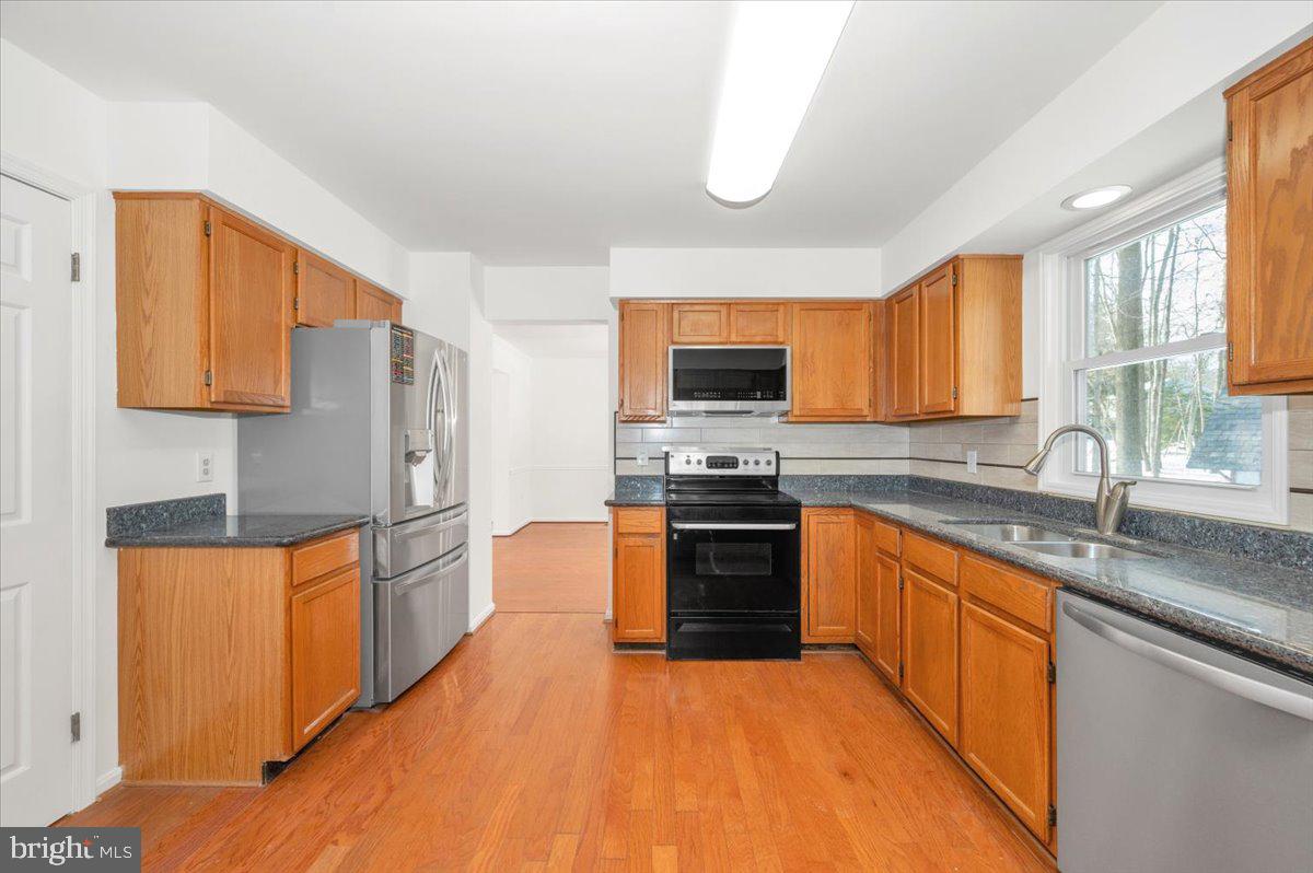 1404 Partridge Lane Bowie, MD 20721 - Photo 22 of 78 a kitchen with stainless steel appliances granite countertop a stove top oven a sink dishwasher a refrigerator and cabinets with wooden floor