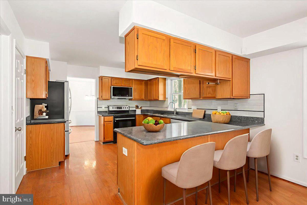 1404 Partridge Lane Bowie, MD 20721 - Photo 24 of 78 a kitchen with stainless steel appliances granite countertop a table chairs stove and refrigerator