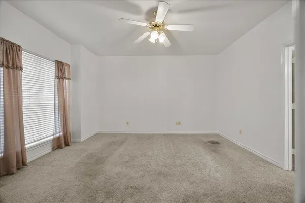 an empty room with a window and a ceiling fan