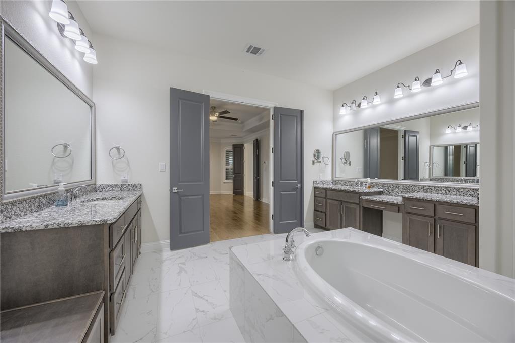 918 Sydney Lane Allen, TX 75013 - Photo 16 of 40 The property features a bathroom with a built-in bathtub, a double vanity with two sinks, and expansive mirrors