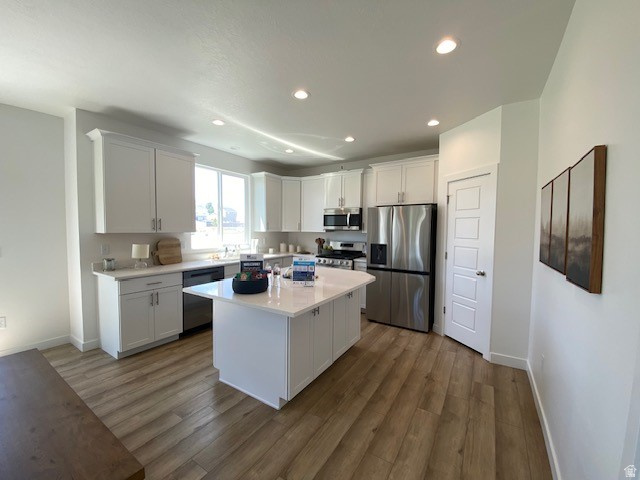 341 Quartz Road, Unit 8037 Tooele, UT 84074 - Photo 9 of 10 Bright kitchen featuring white cabinetry, a central island, stainless steel appliances, recessed lighting, and wood-finish flooring