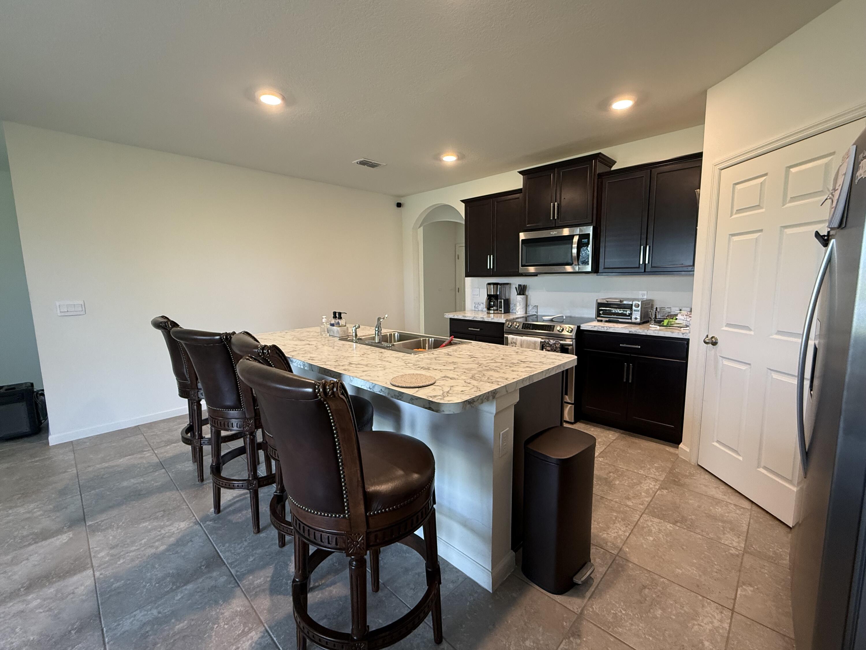 9511 Potomac Drive Fort Pierce, FL 34945 - Photo 10 of 26 a kitchen with a sink a microwave a refrigerator and cabinets