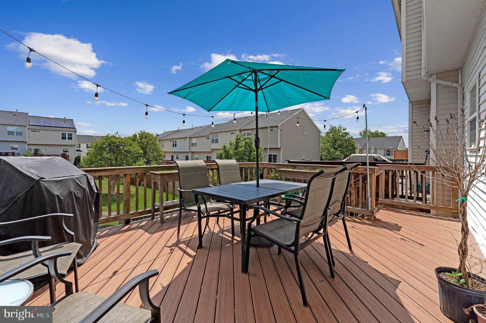 590 Tuliptree Square Northeast Leesburg, VA 20176 - Photo 19 of 54 a view of a roof deck with table and chairs under an umbrella with wooden floor