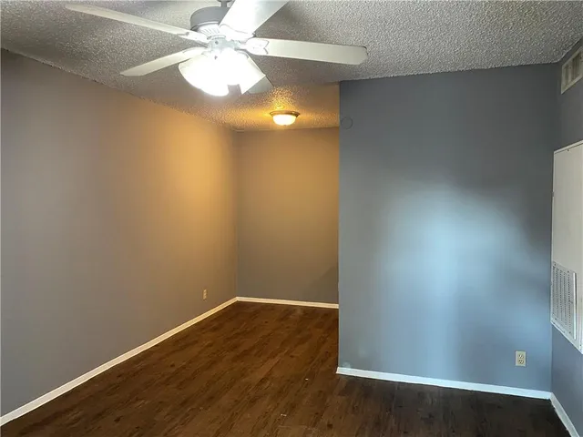 a view of an empty room with chandelier fan and wooden floor