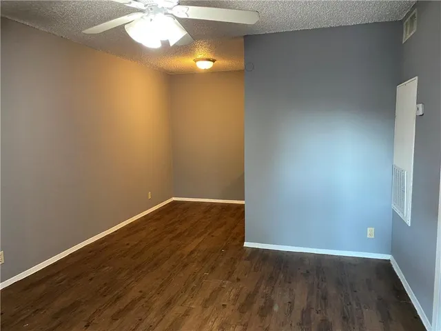 an empty room with wooden floor and fan