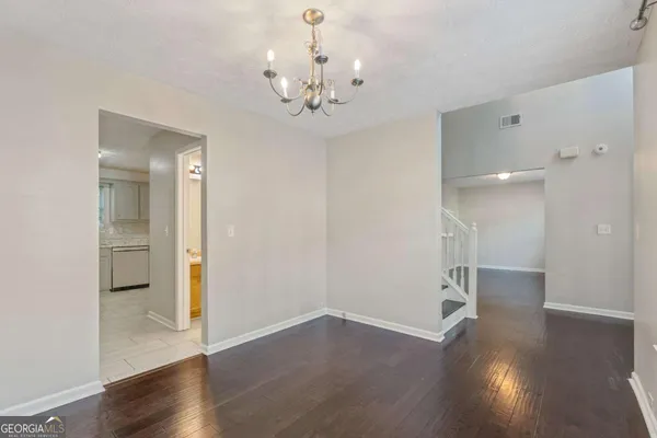 a view of an empty room with wooden floor and a chandelier