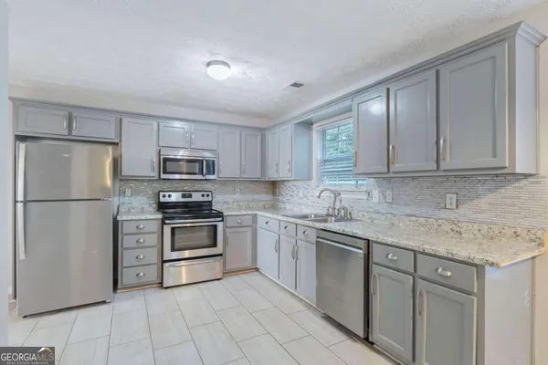 a kitchen with stainless steel appliances granite countertop a refrigerator sink and stove
