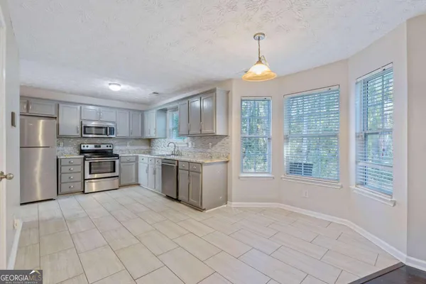 a kitchen with stainless steel appliances granite countertop a stove a sink dishwasher a refrigerator and white cabinets with wooden floor