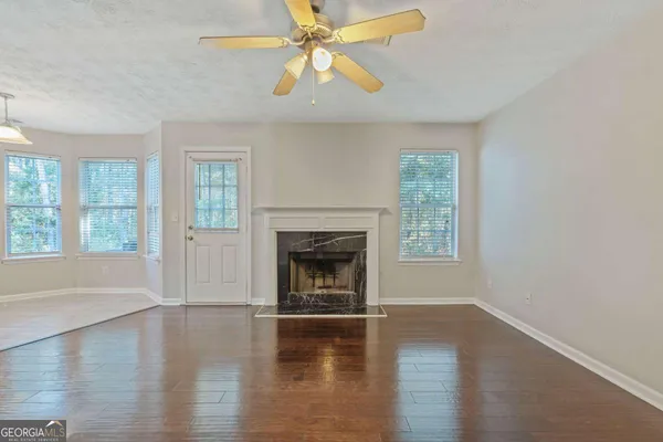 an empty room with windows fireplace and wooden floor
