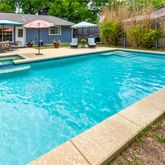 a swimming pool view with a seating space and a garden view