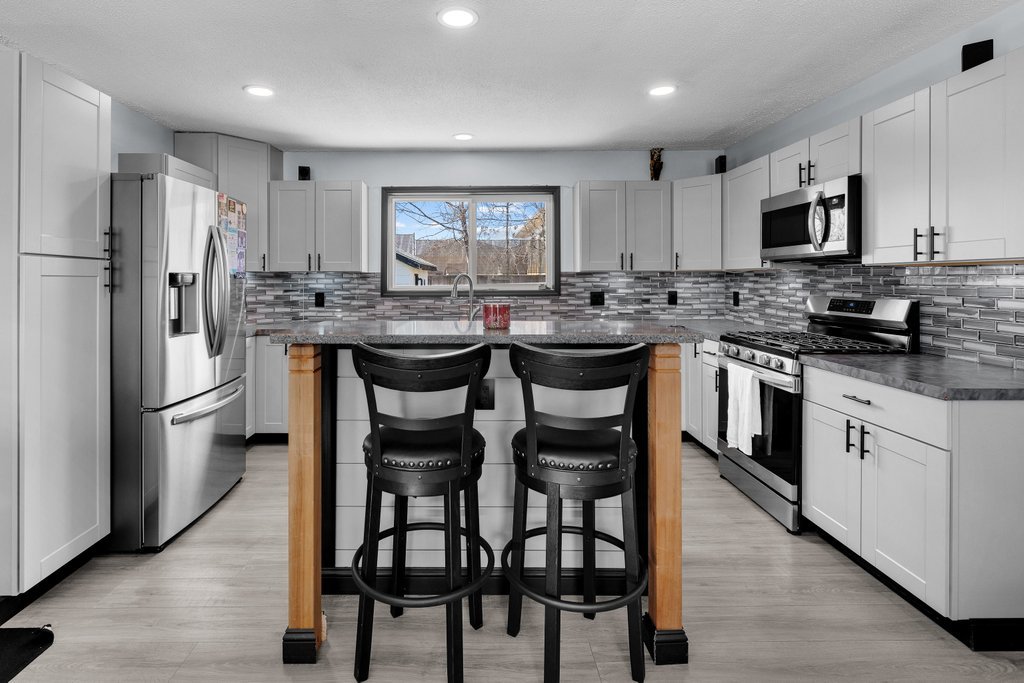 8012 10th Street West Rock Island, IL 61201 - Photo 13 of 27 a kitchen with stainless steel appliances granite countertop a table chairs stove microwave and cabinets