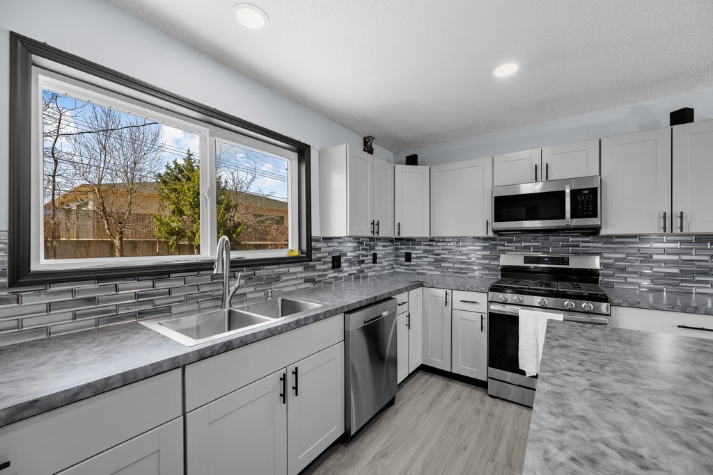 8012 10th Street West Rock Island, IL 61201 - Photo 17 of 27 a kitchen with stainless steel appliances granite countertop a sink and a stove top oven with wooden floor