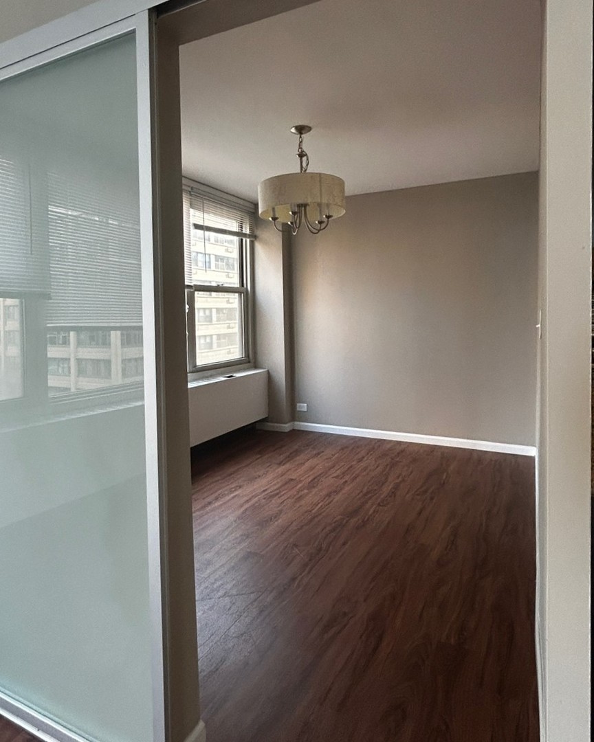 860 North Dewitt Place, Unit 1501 Chicago, IL 60611 - Photo 4 of 17 an empty room with wooden floor and windows