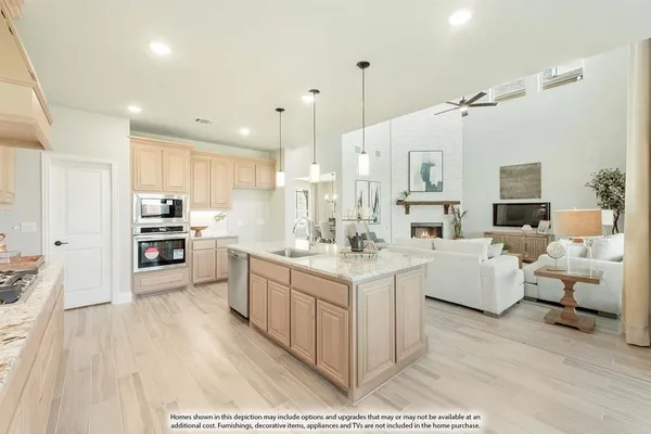 a large kitchen with kitchen island a sink dishwasher a stove a refrigerator and white cabinets with wooden floor