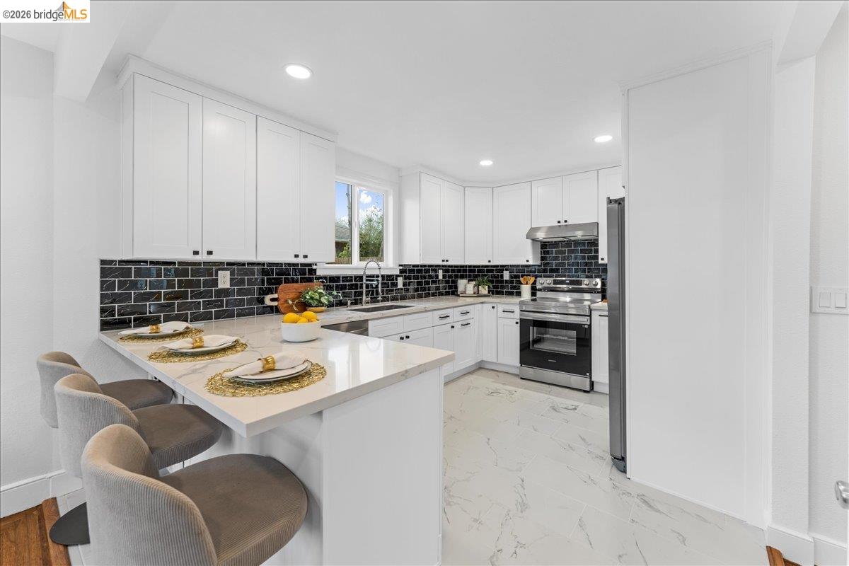 2717 Mabel Street Berkeley, CA 94702 - Photo 38 of 60 a kitchen with a dining table chairs stove and white kitchen