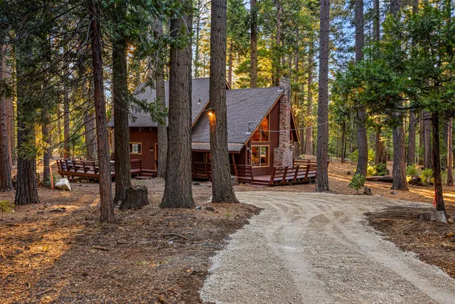 a view of a house with a large tree and wooden fence