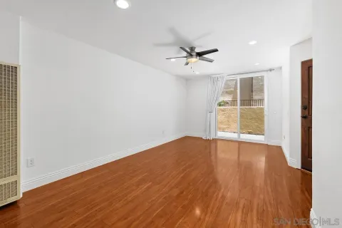 an empty room with wooden floor chandelier fan and windows