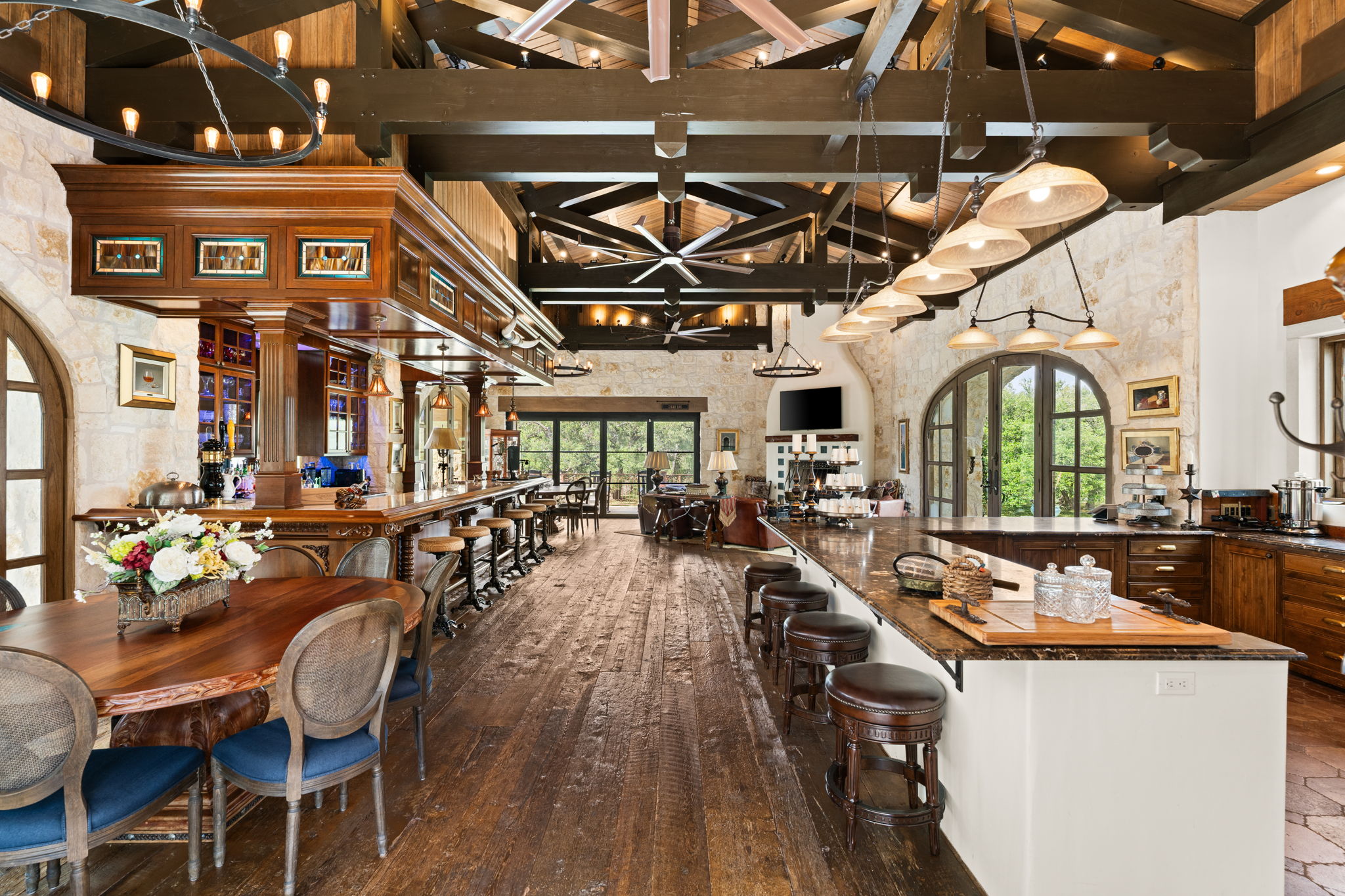 11941 Overlook Pass Austin, TX 78738 - Photo 35 of 40 Expansive open-concept living area featuring a full-service bar, stone accent walls, vaulted wood beam ceilings, wood-finish flooring, and arched windows